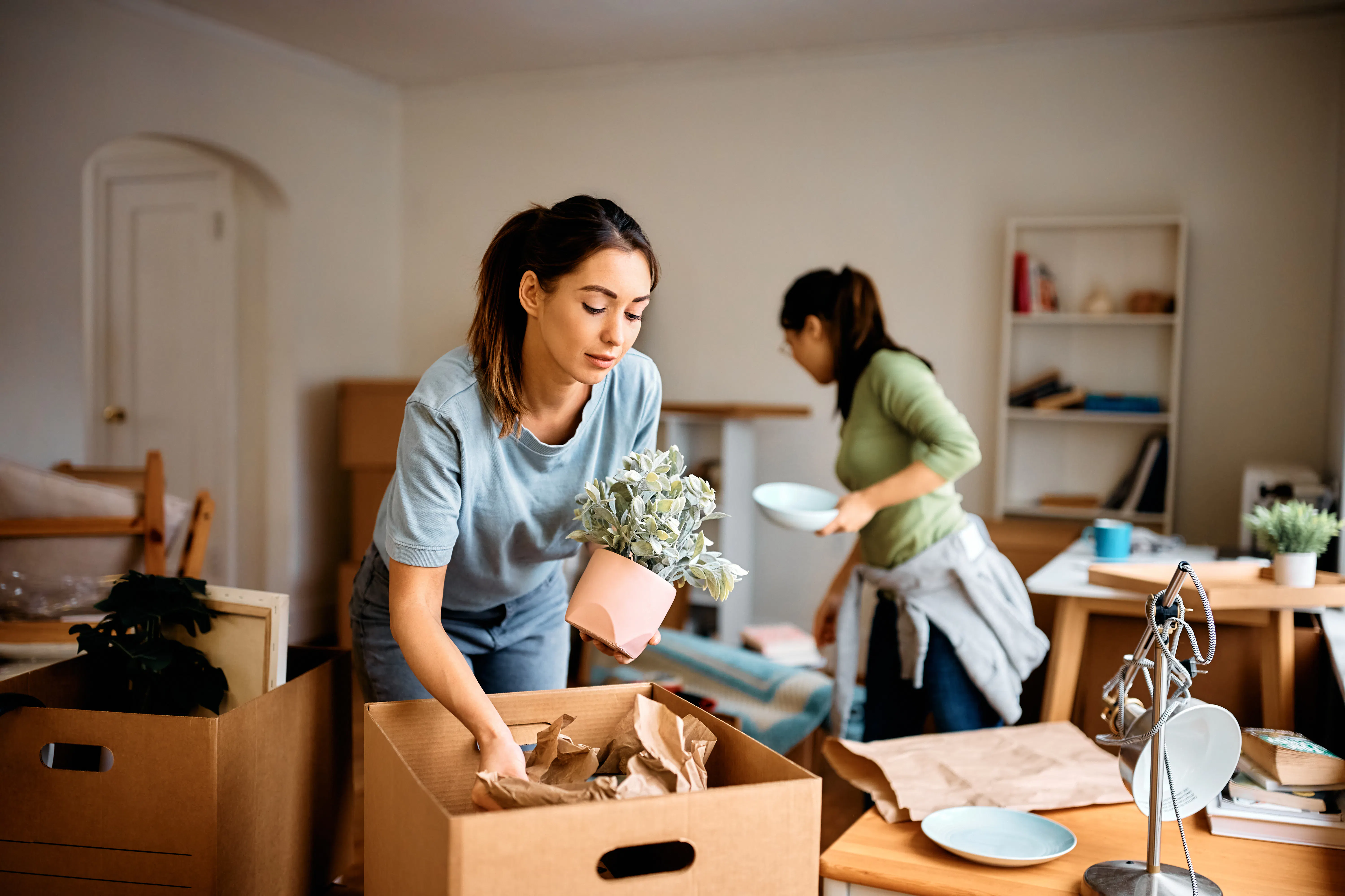 Young woman and her friend unpacking their belongings while moving into an apartment.