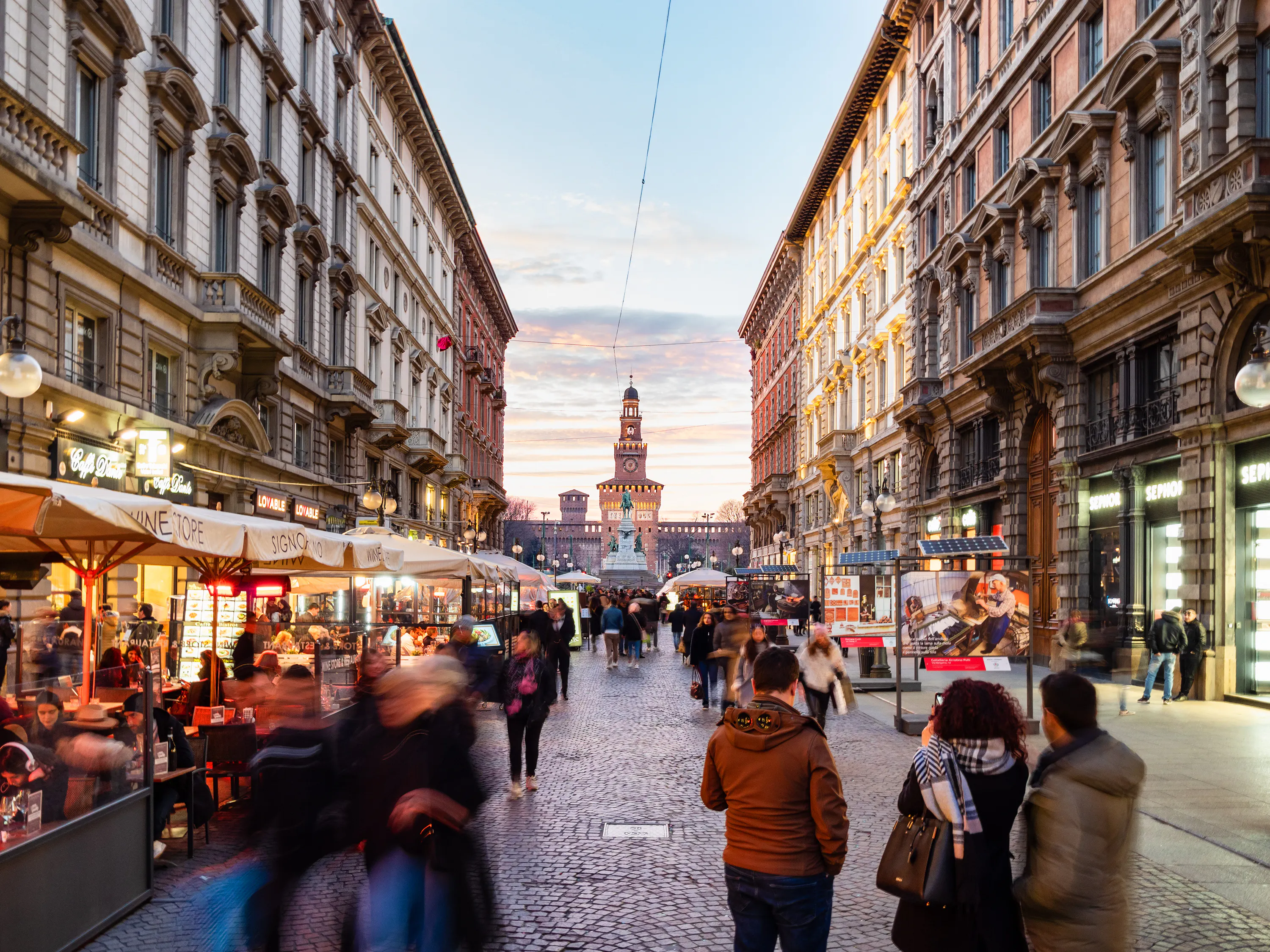MILAN, ITALY: outdoor restaurants on street Via Dante and view of Castello Sforzesco (Sforza Castle) in Milan in evening.