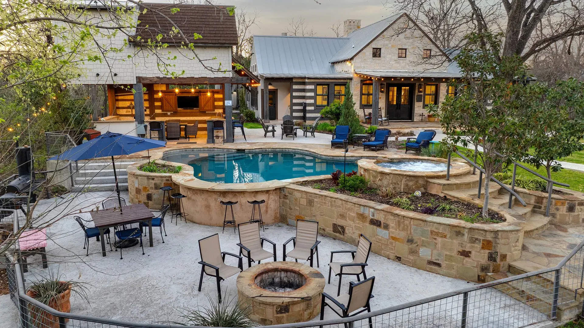 Aerial view of a Bach Bros Properties rental in Fredericksburg, Texas, with a pool, hot tub, fire pit and covered outdoor kitchen
