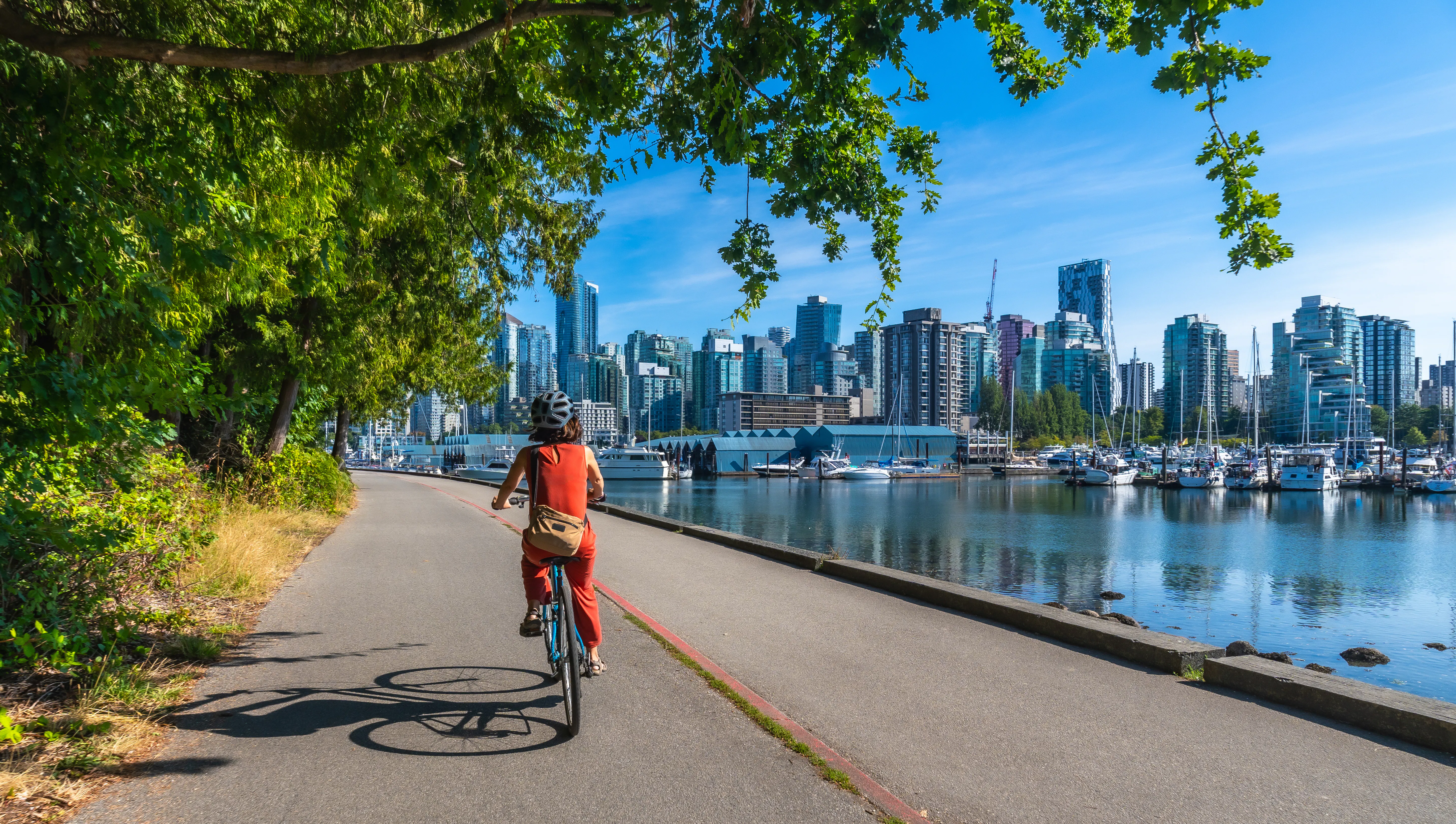 Woman cycling in stanley park with vancouver skyline in background