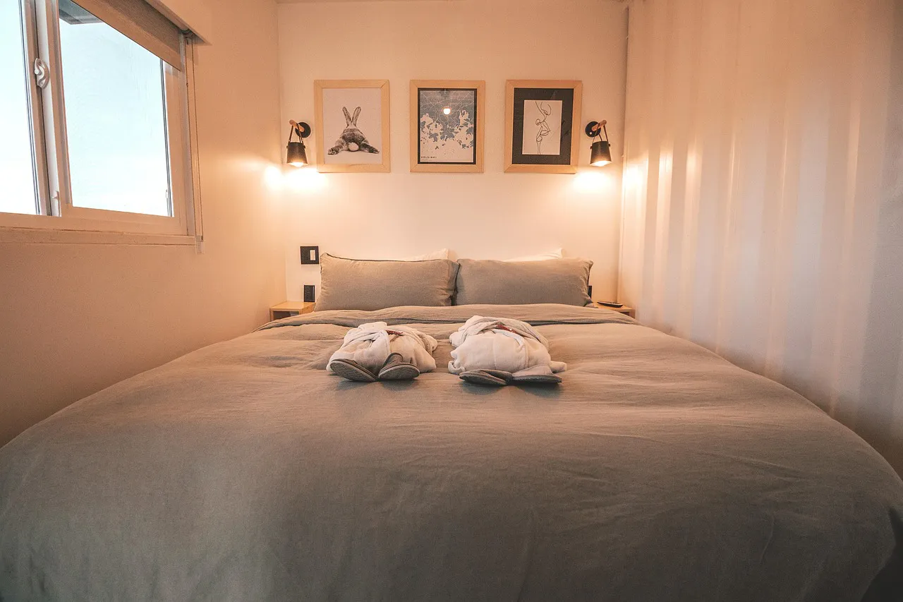 A cozy bedroom with a grey duvet, two white bathrobes on the bed