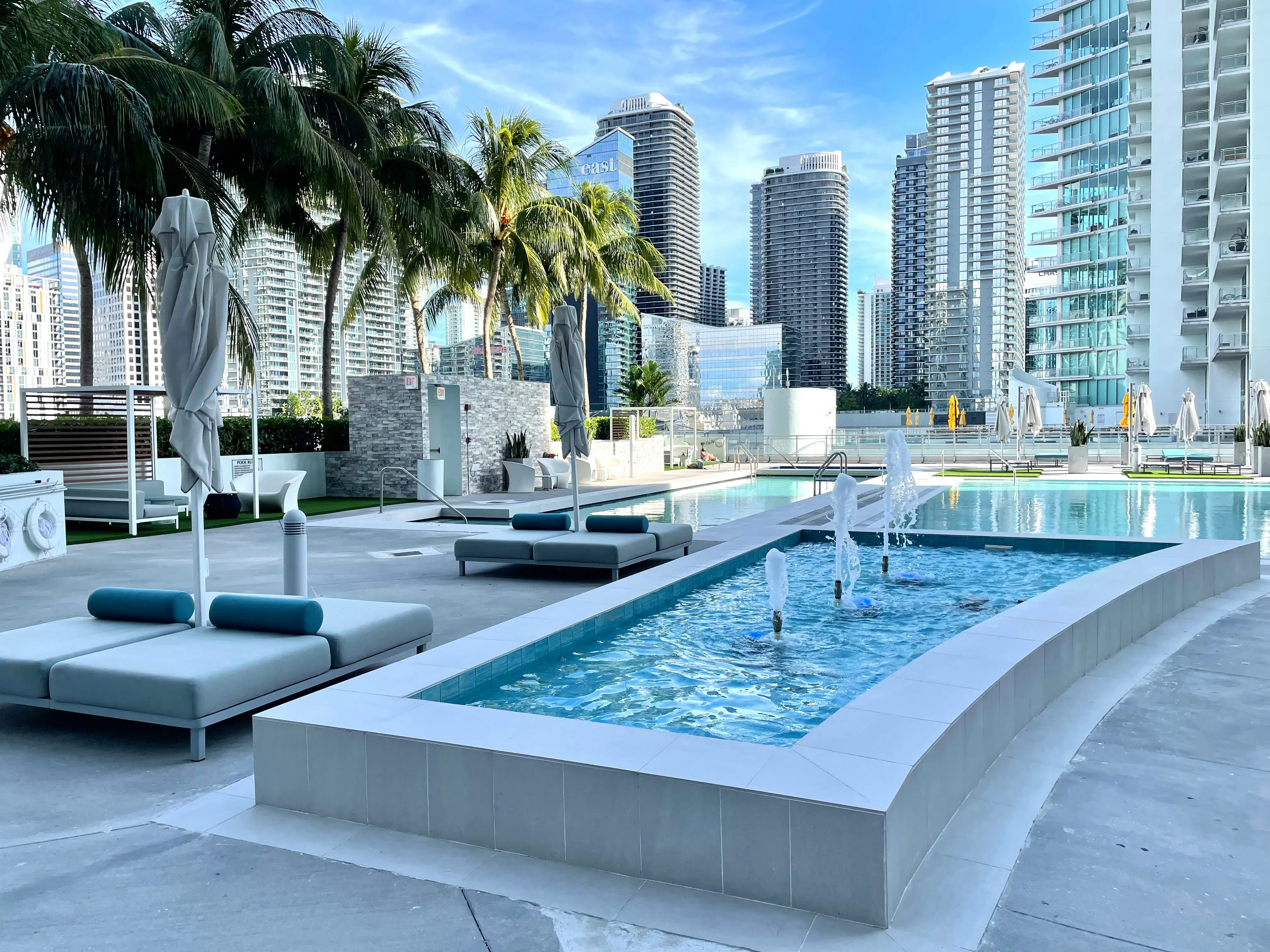 A luxury rooftop pool deck in Miami with lounge chairs and water fountains
