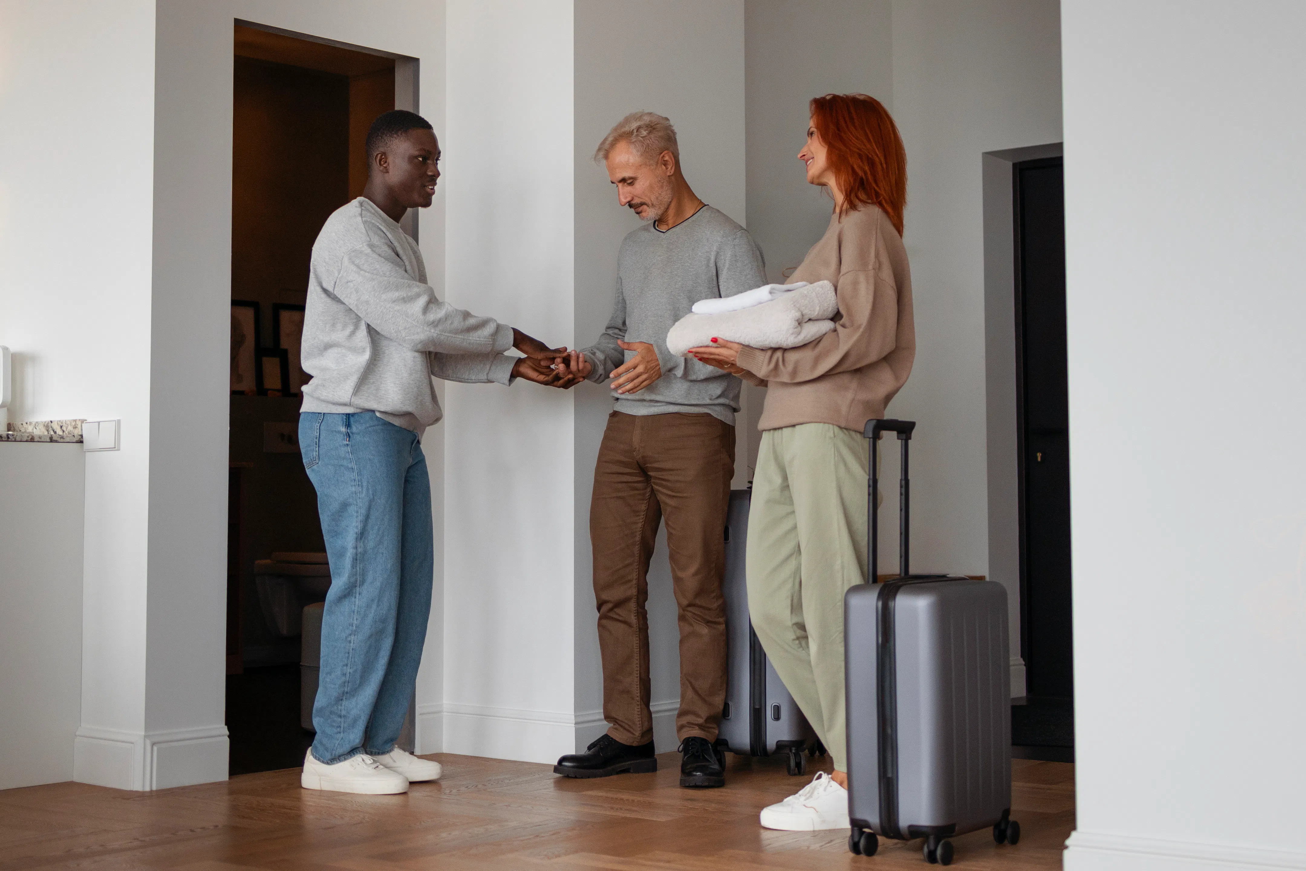 A short-term rental host welcoming a couple into a modern apartment