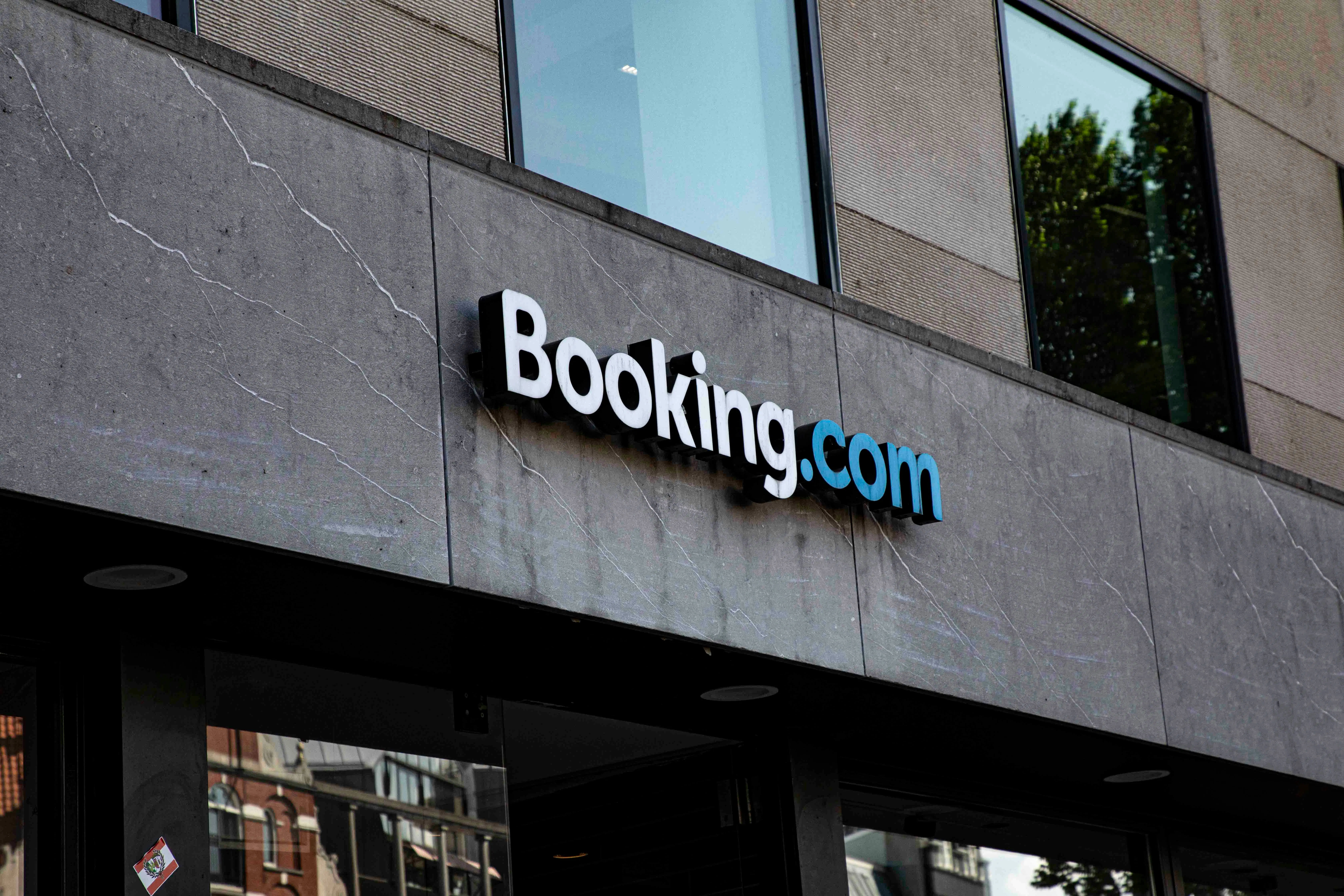 The Booking.com logo sign mounted on a gray concrete building exterior above the entrance.