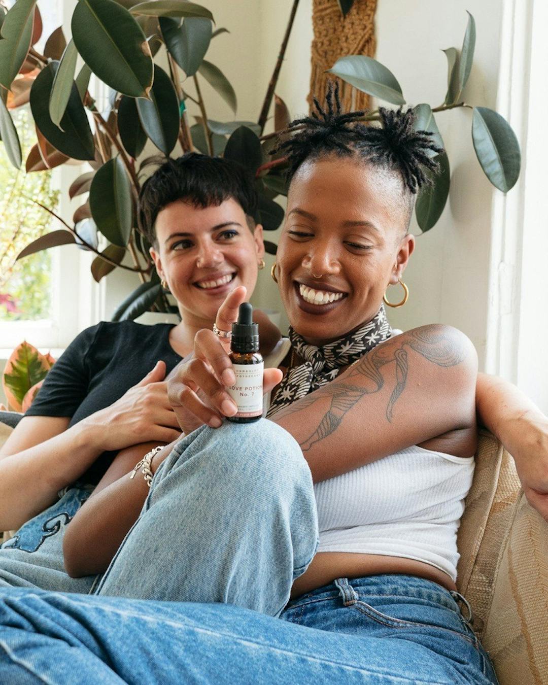 Two people laughing as one is holding a cannabis tincture 