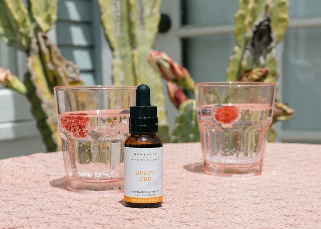 A tincture on a table next to two glasses