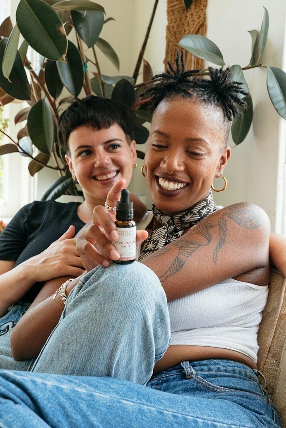 Two people laughing as one is holding a cannabis tincture 