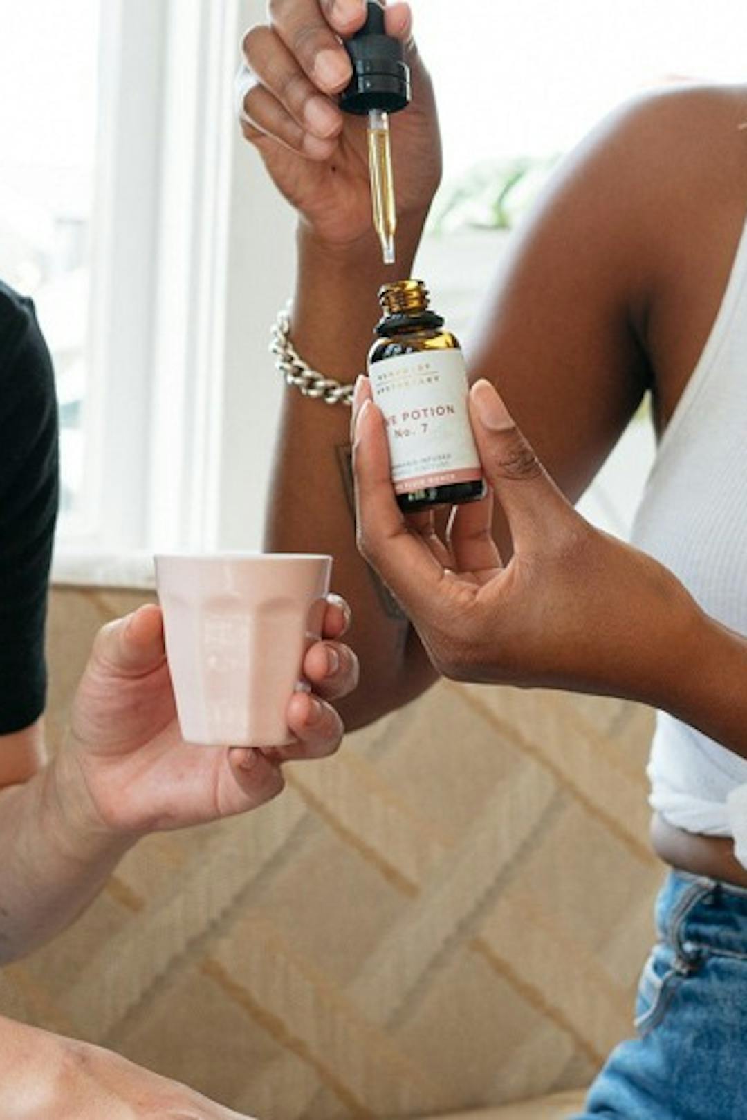 Two people holding a tincture putting a drop into their cup