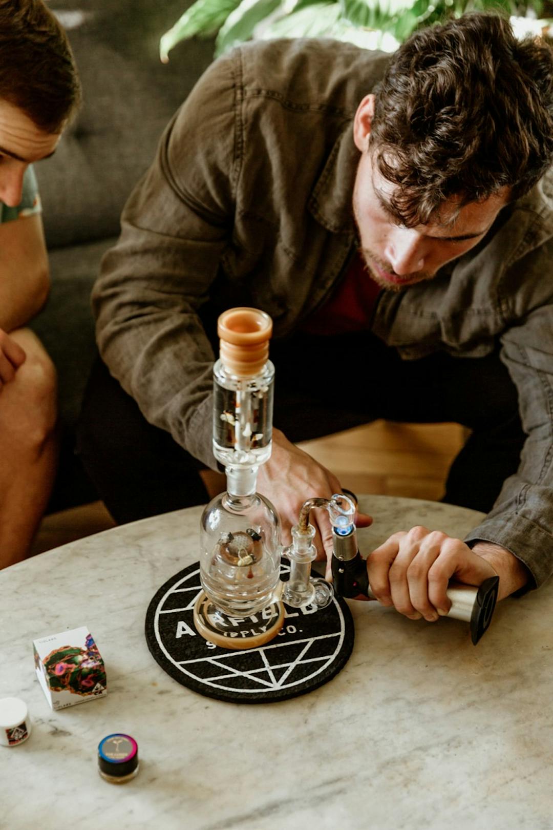 Two men torching the bong preparing for a dab