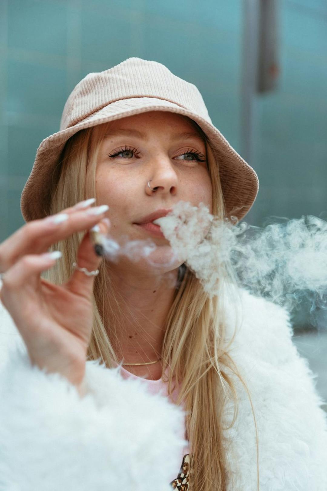 Woman with a bucket hat smoking a joint