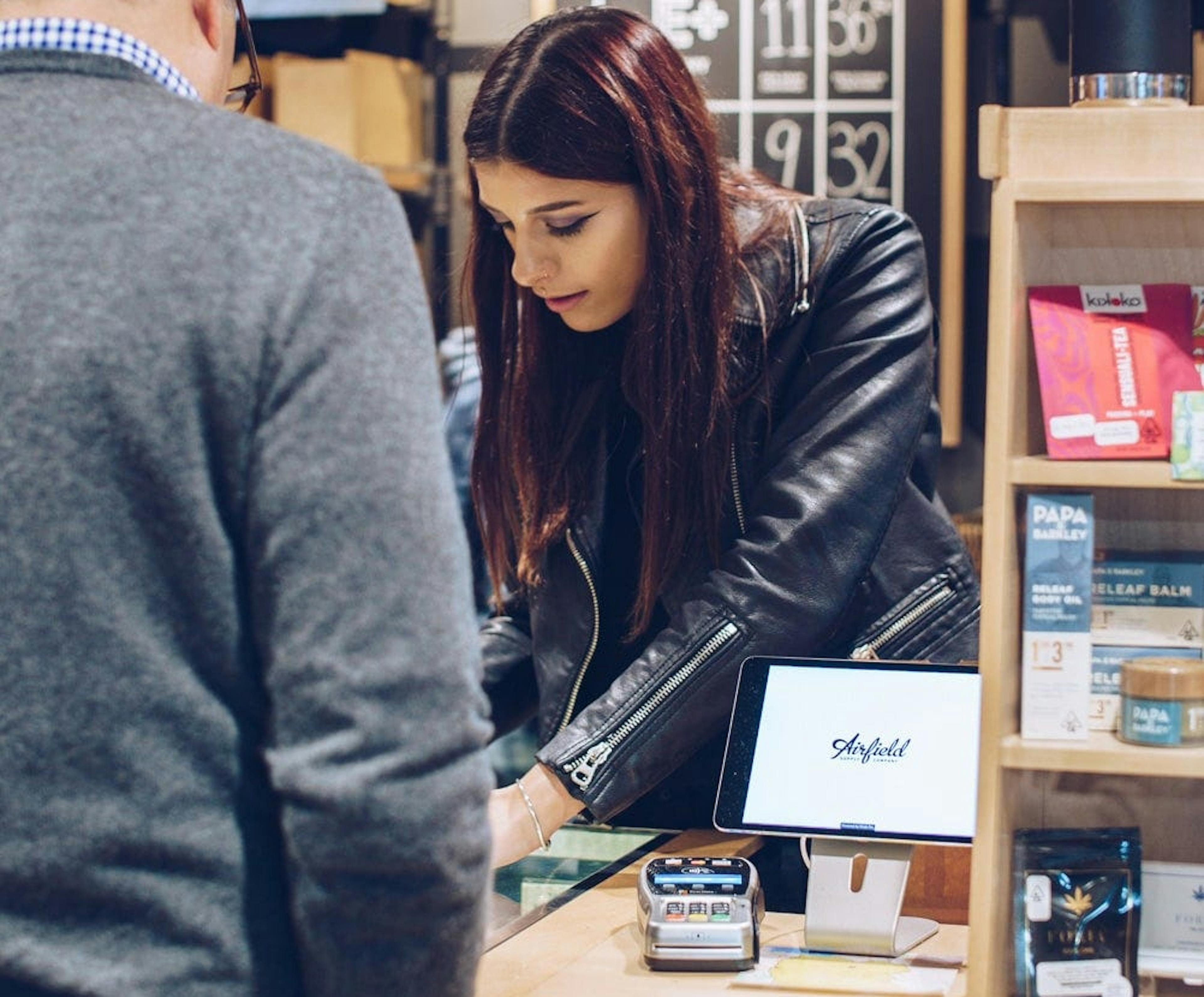 Woman budtender helping customer at checkout