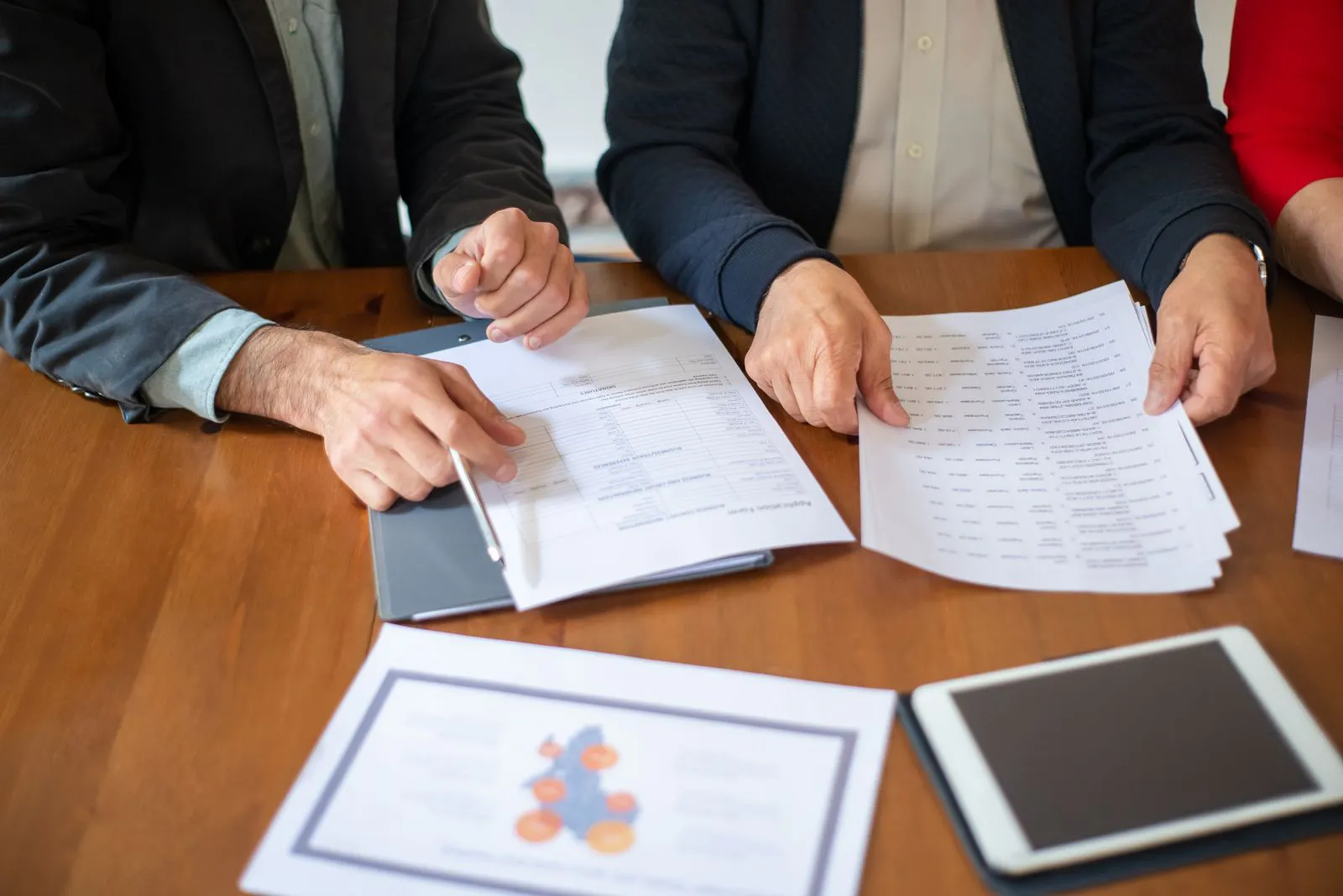 Two colleagues reviewing contract and compliance documents together during a vendor evaluation meeting