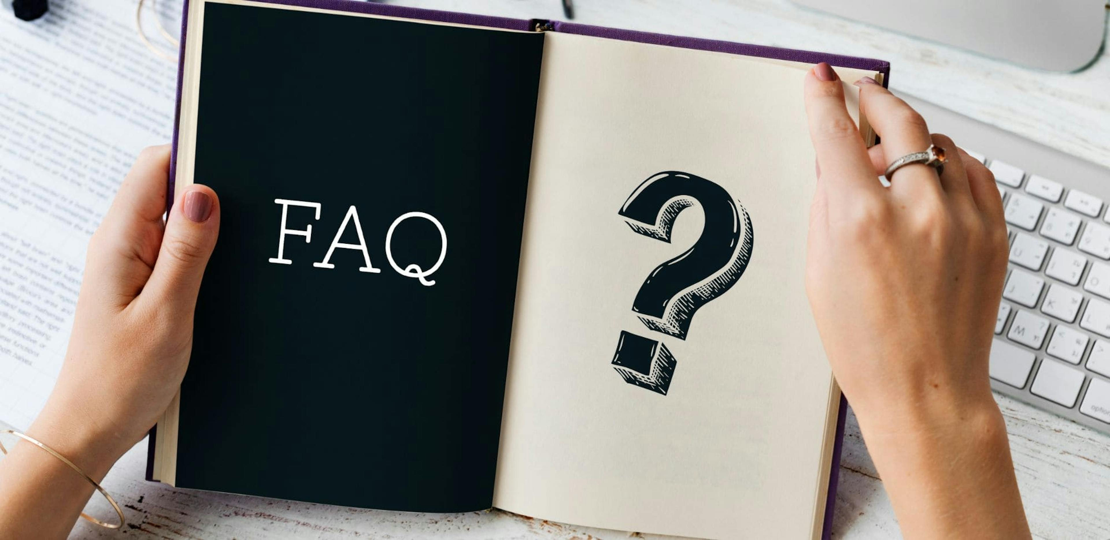 A person holding an open book. On the left page, the word 'FAQ' is displayed in white on a black background. On the right page, there is a large black question mark drawn on a white background.