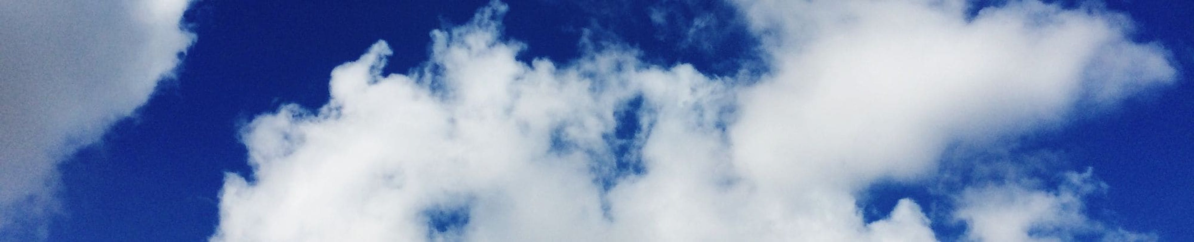 Low angle view of white clouds in a clear blue sky.