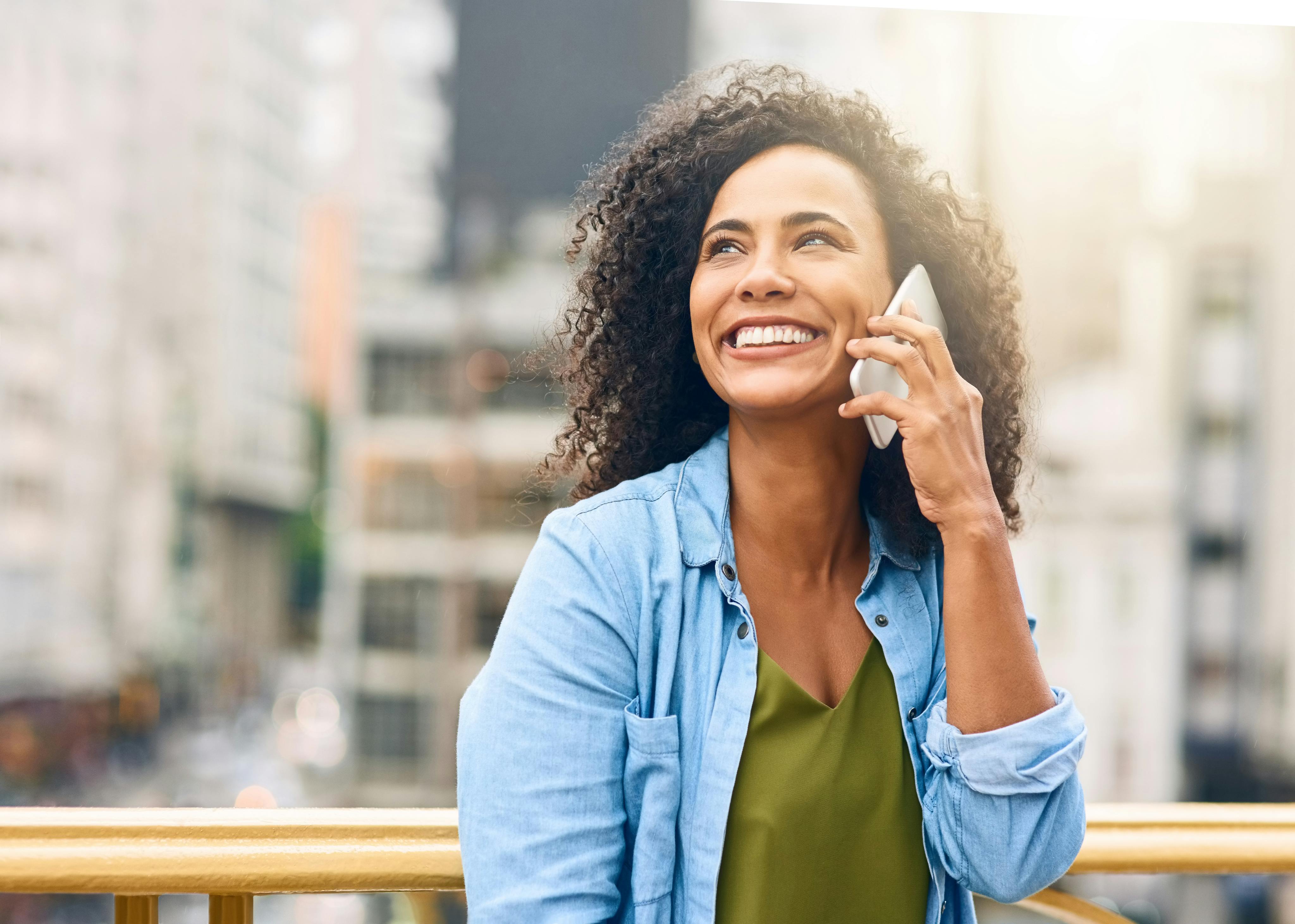 Woman in a city smiling and talking on the phone