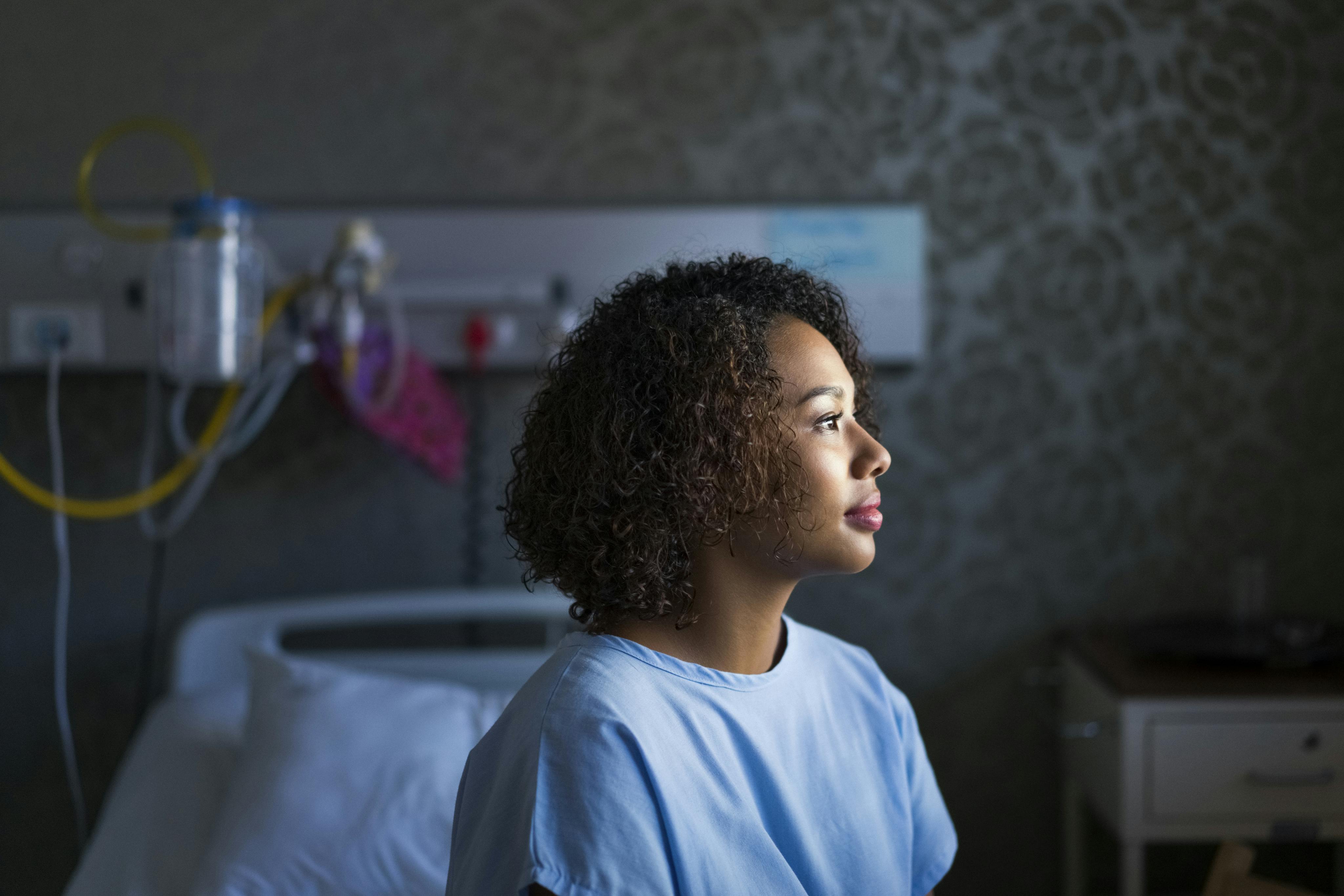 Woman in hospital gown looking out a window