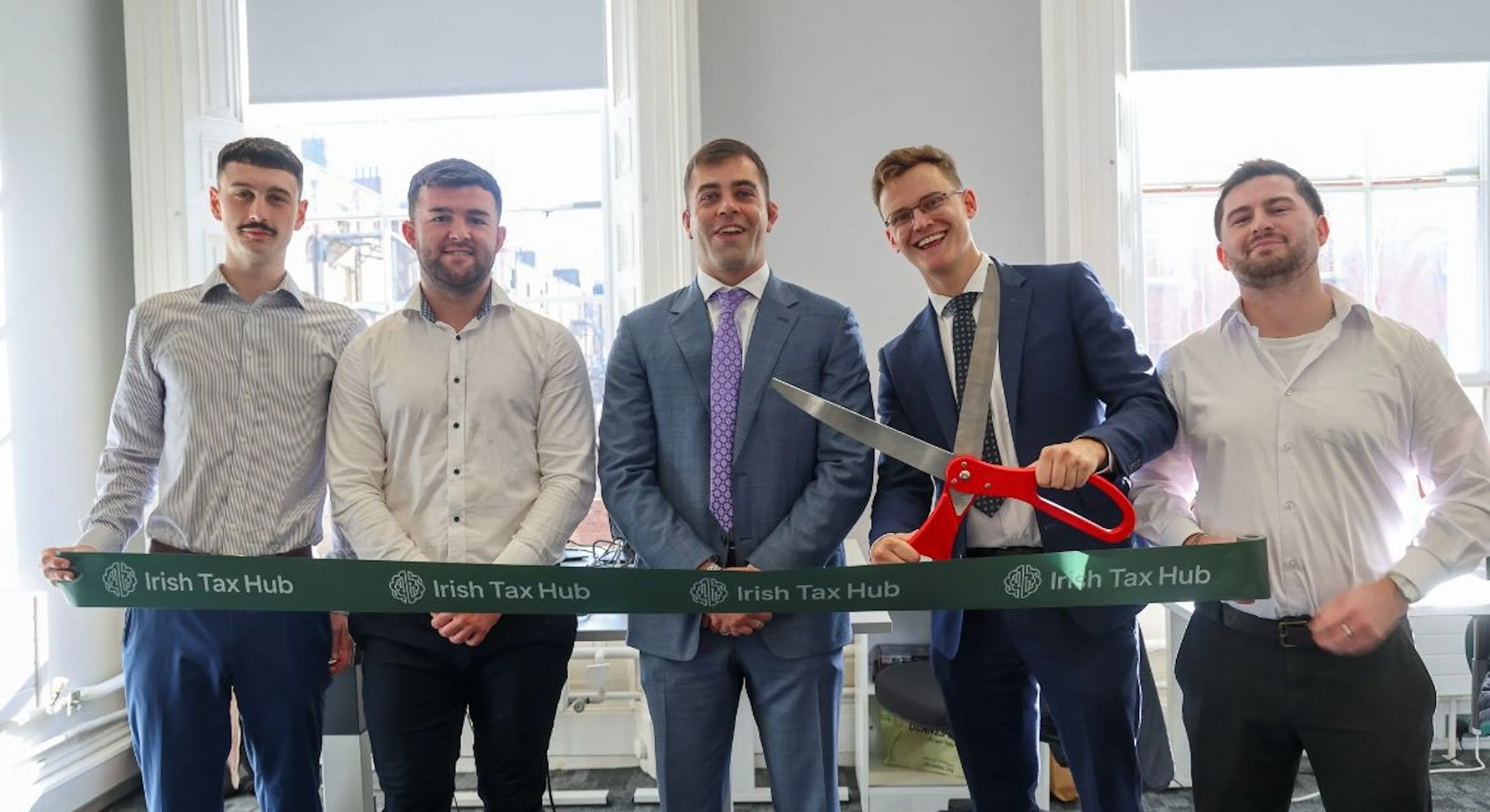 Albert Dolan TD cutting the ribbon with Damien Roche and the Irish Tax Hub team at the official opening of the new office