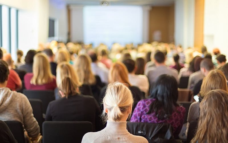 researchers watching academic research being presented at an international conference
