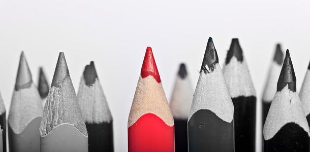 One red pencil in a group of grayscale pencils represents the need for a grammar glossary for authors
