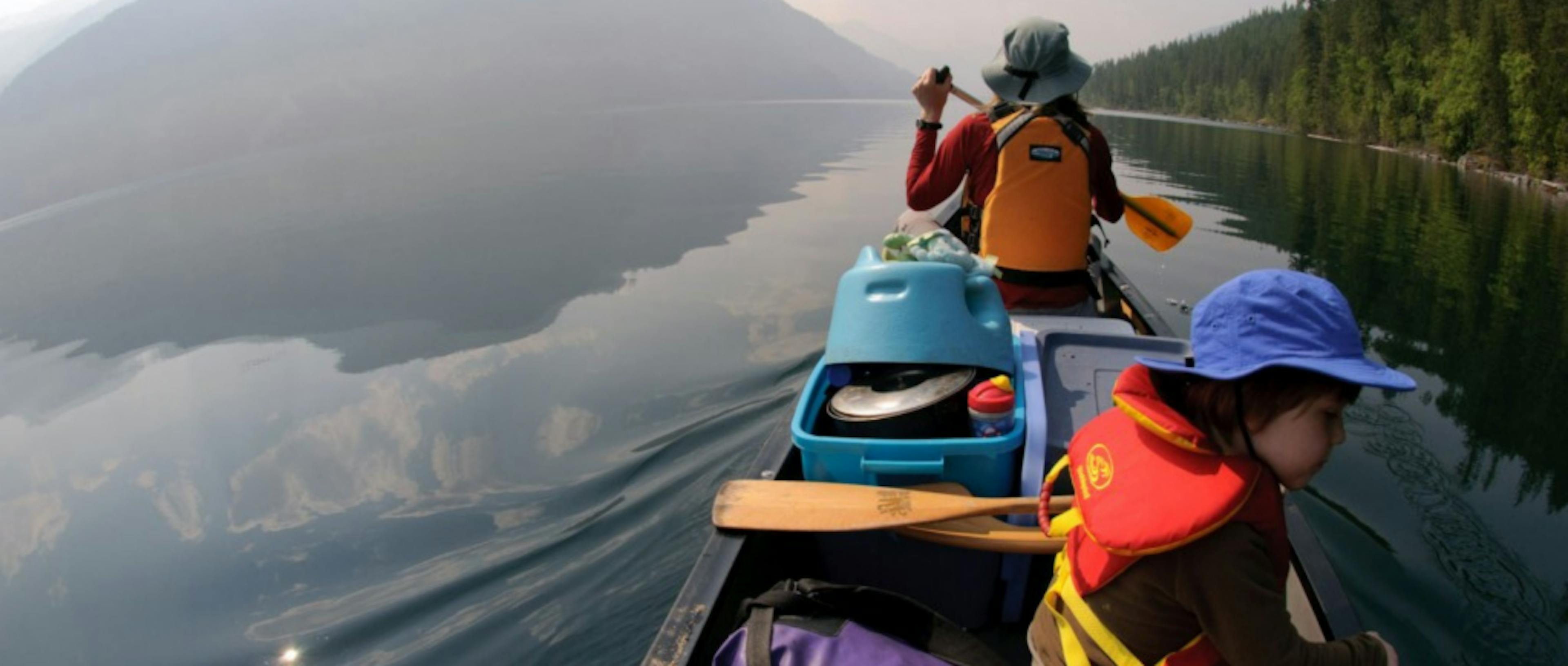 An adult and child in a canoe on a still lake