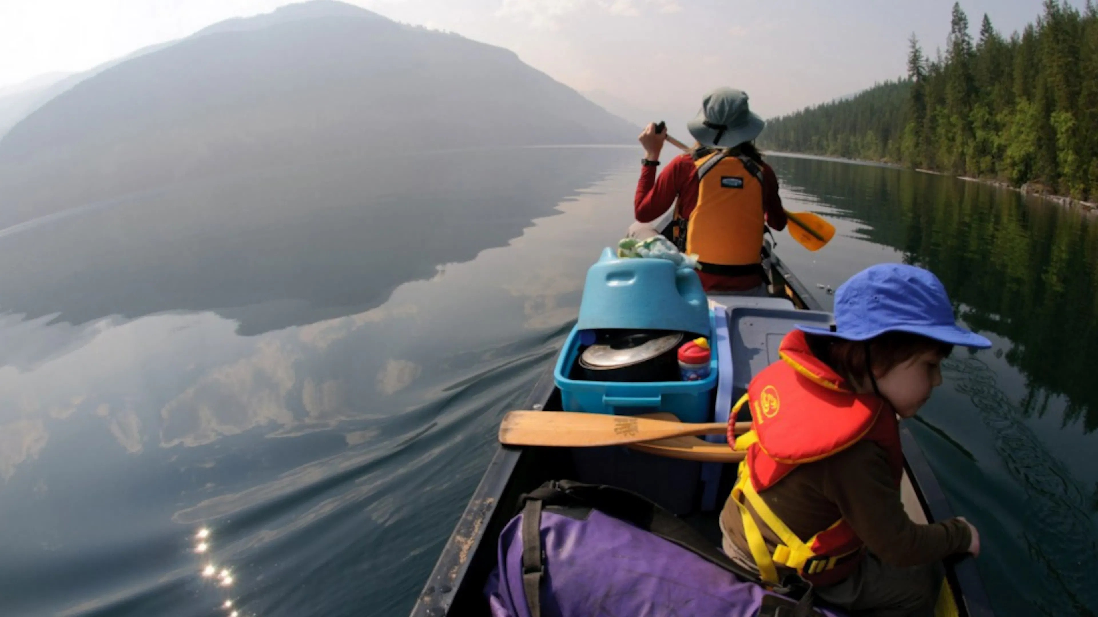 An adult and child in a canoe on a still lake