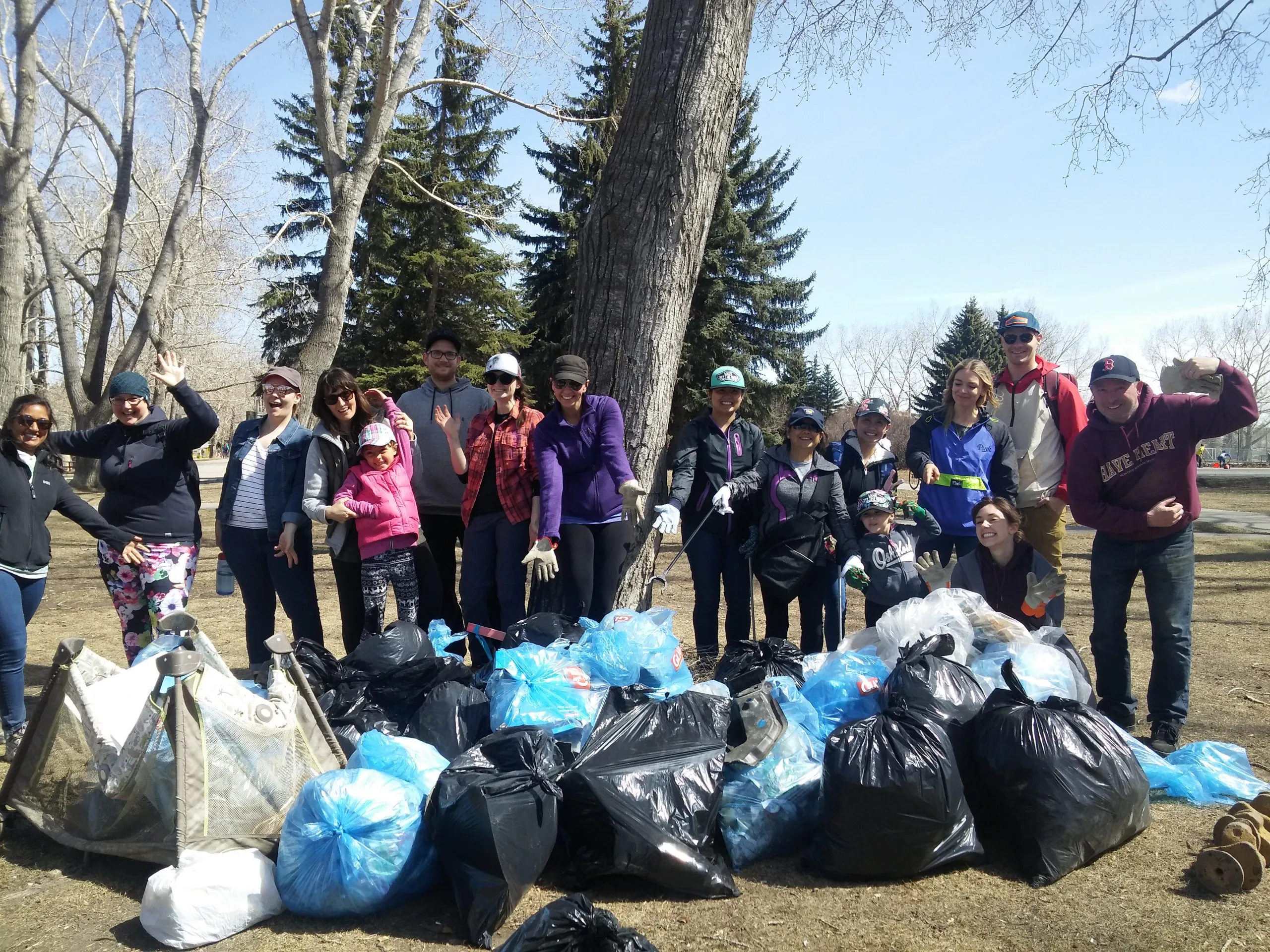 A group of people standing in front of many bags of garbage.