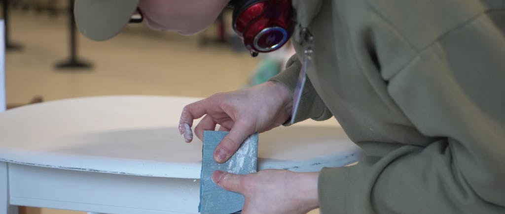 Person putting tape on a white table