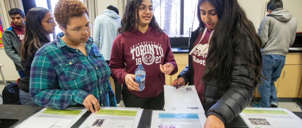 Three students looking at flyers at a table
