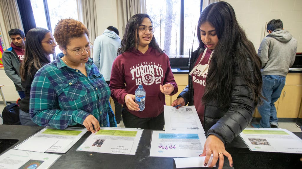 Three students looking at flyers at a table