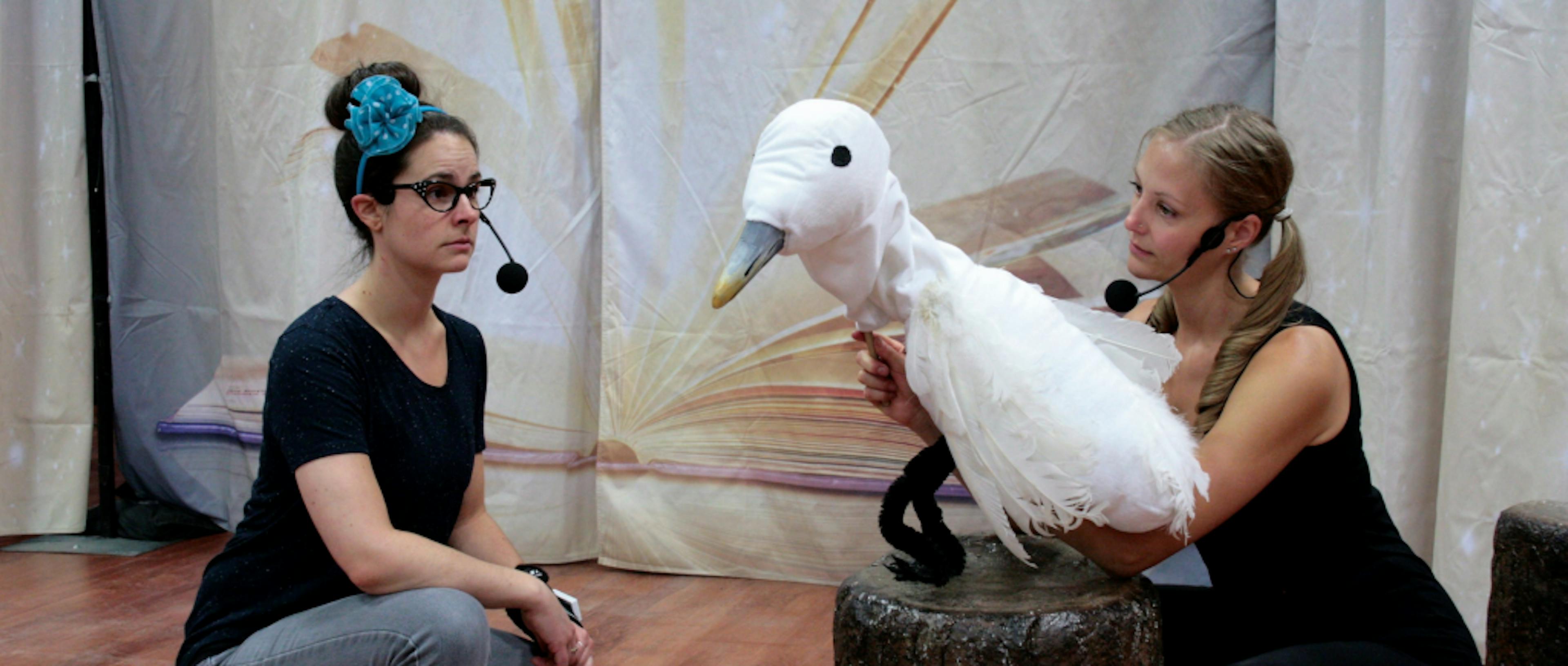 Two people on a stage and one is holding a bird puppet