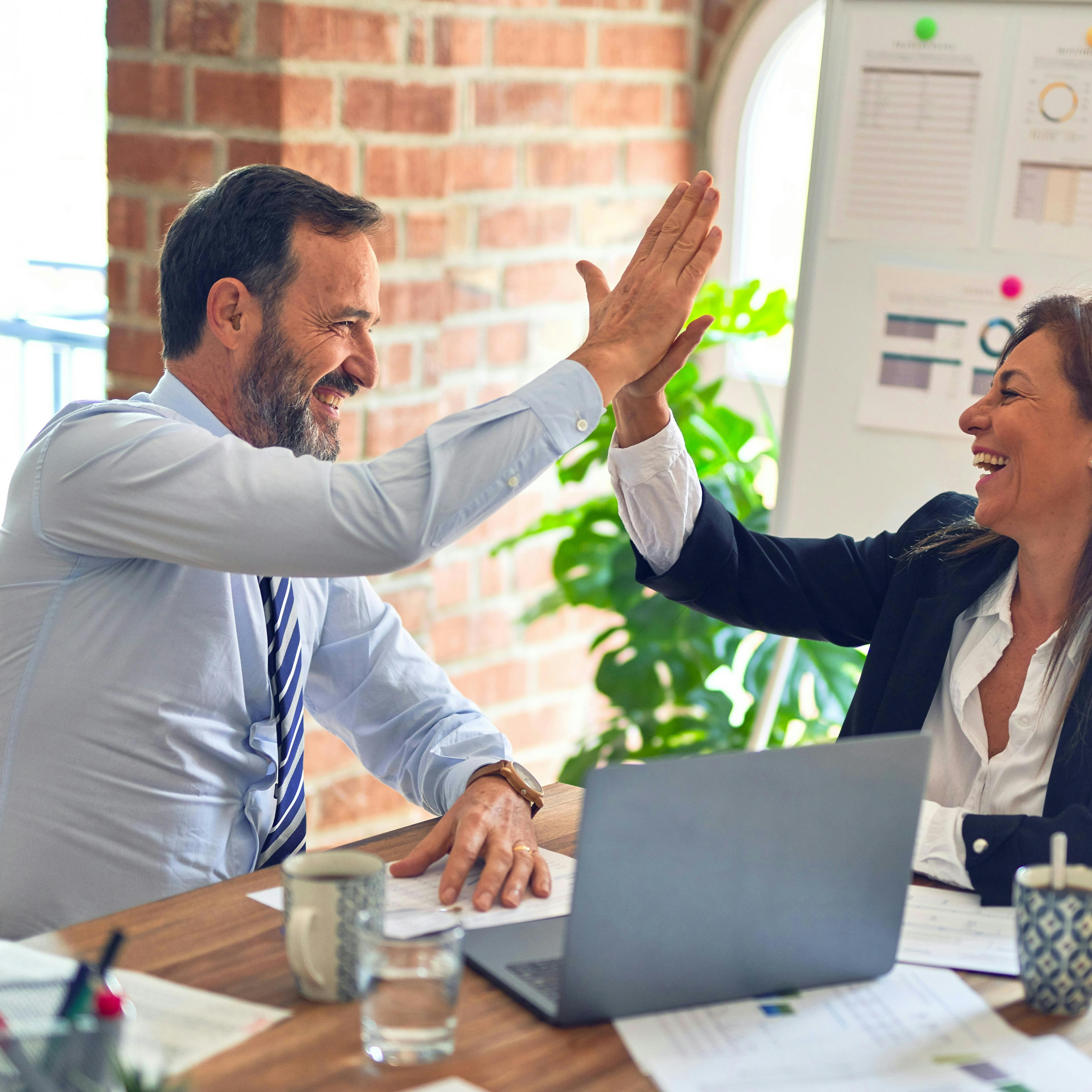 Business woman and man celebrating their collaboration. Photo by krakenimages on Unsplash