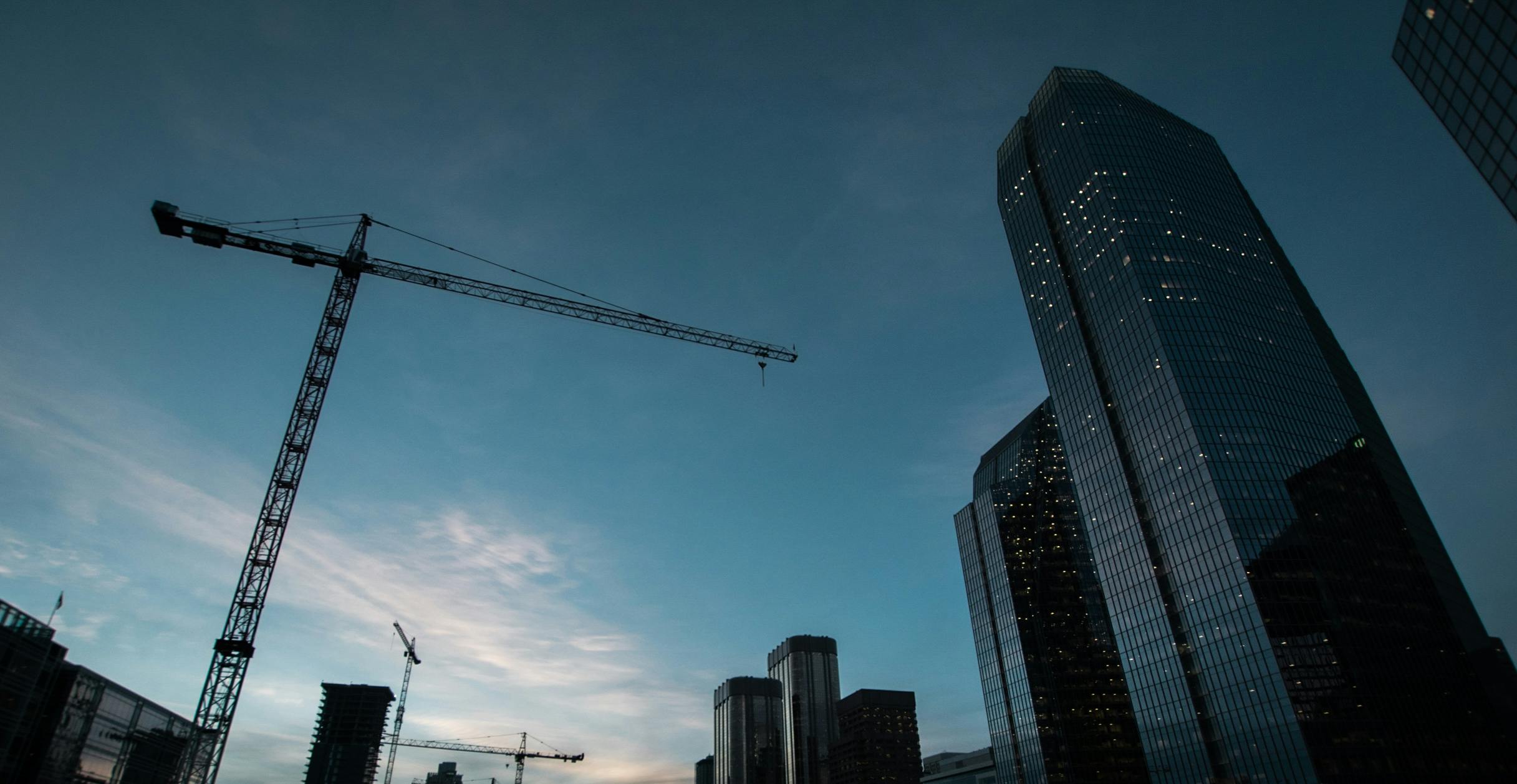 A crane and skyscraper against a blue evening sky
