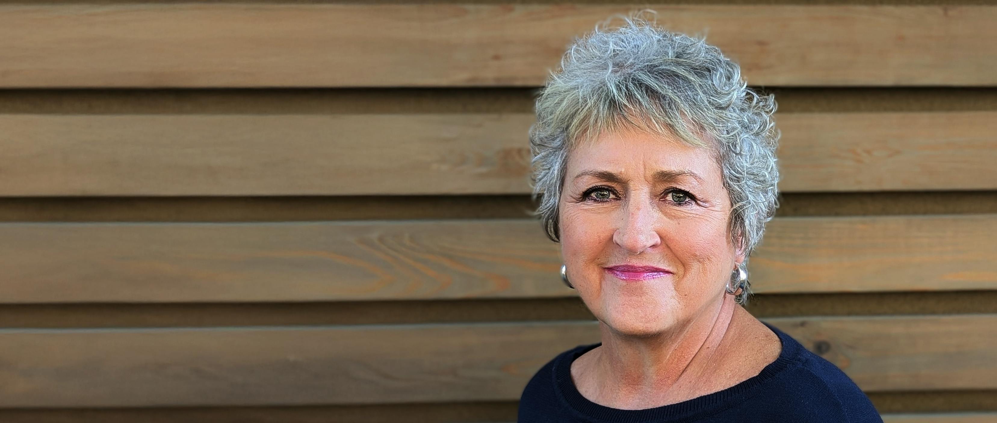 A women standing in front of a wooden wall