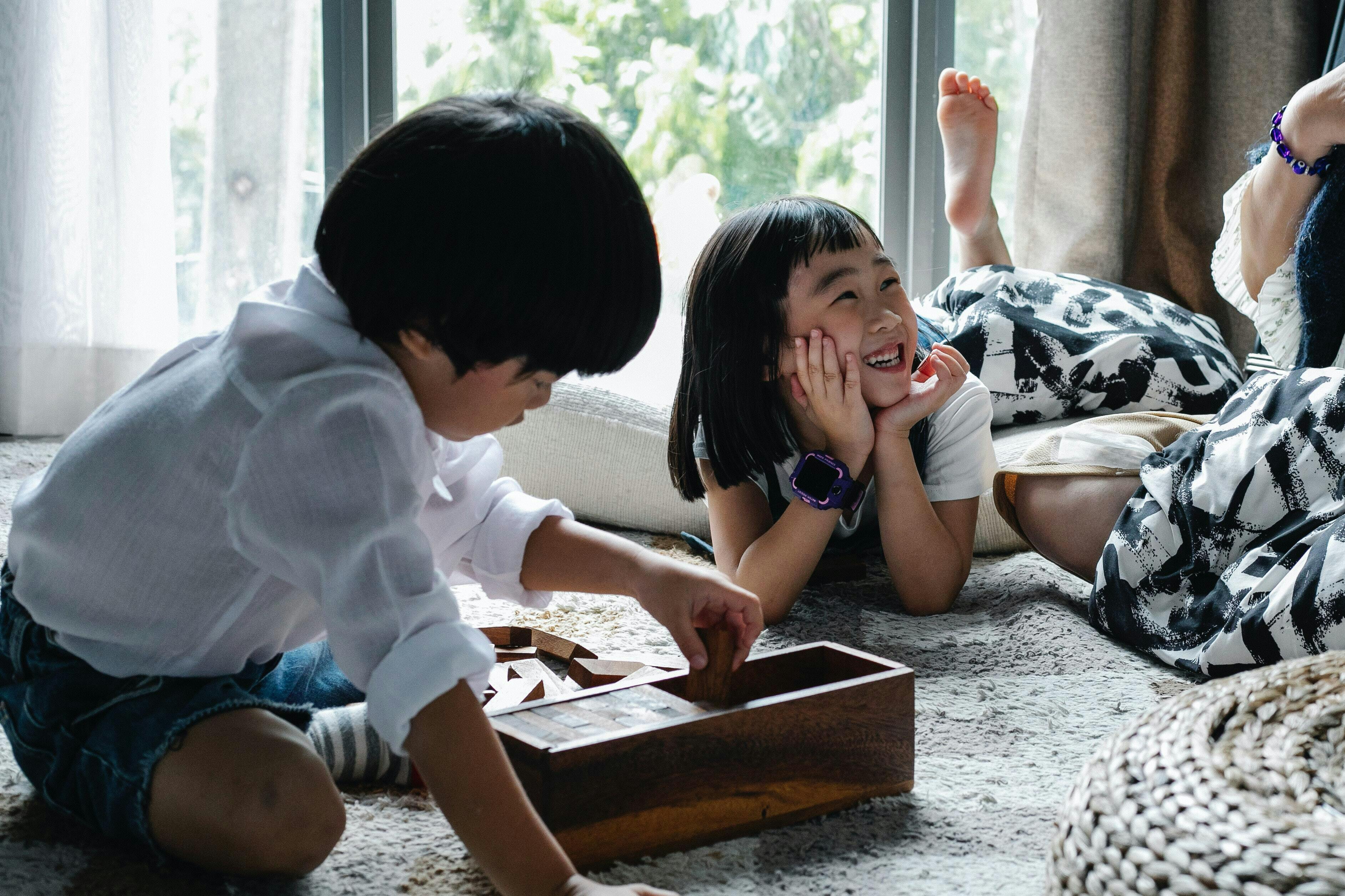 Children play in front of window with caregiver