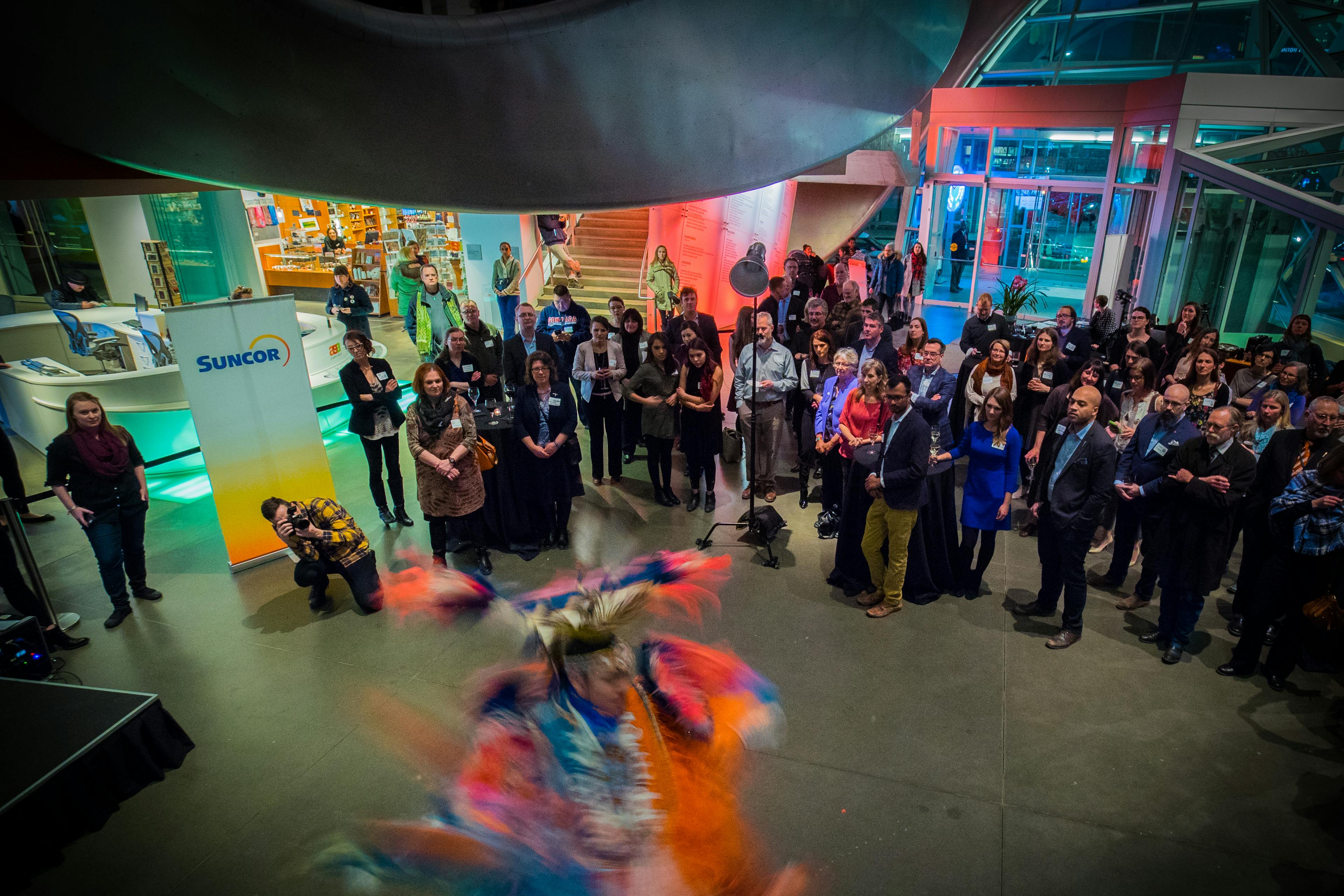 Room of people watch an Indigenous dancer