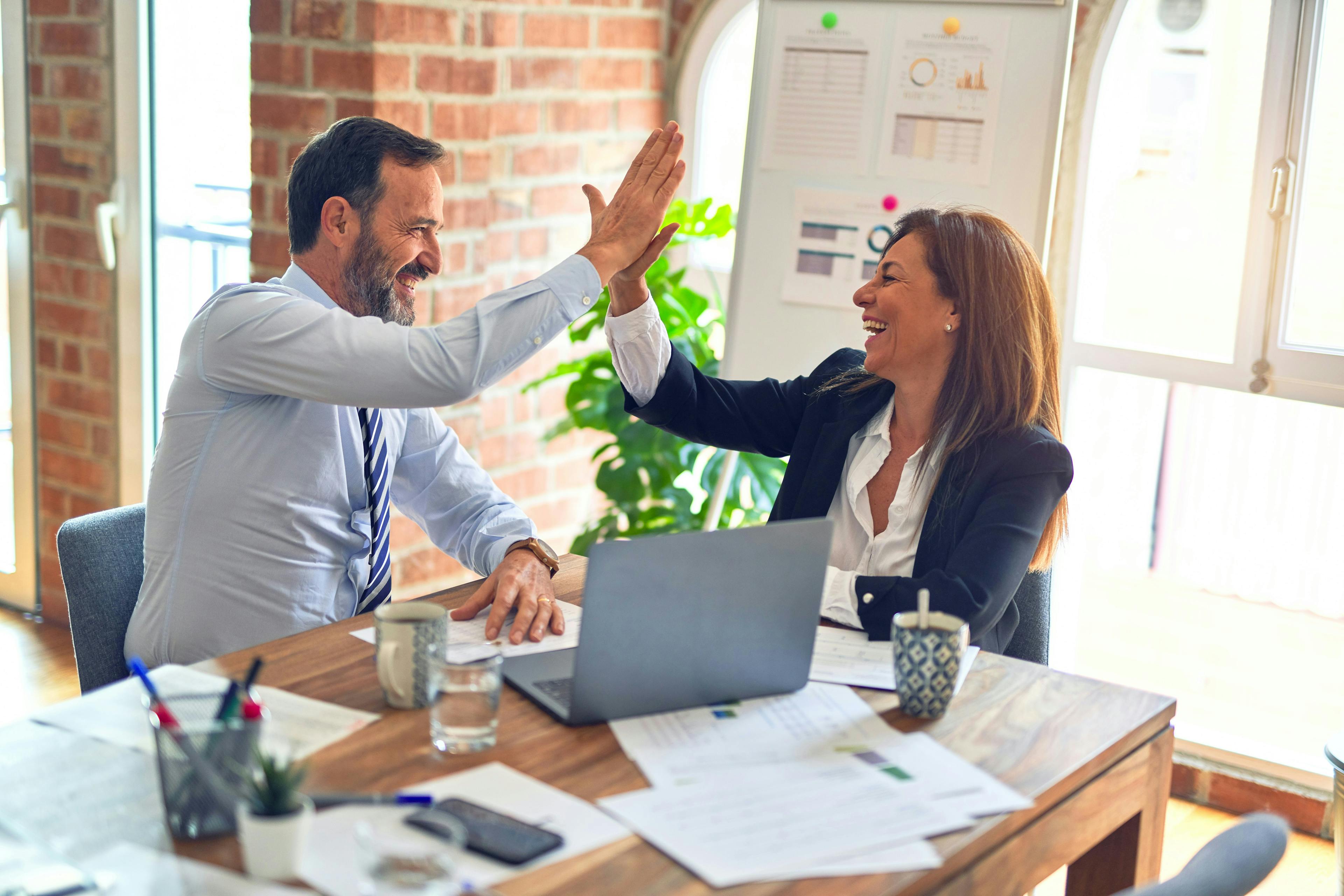 Business woman and man celebrating their collaboration. Photo by krakenimages on Unsplash