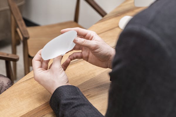 Médecin qui tient une prothèse mammaire de taille intérmédiaire.