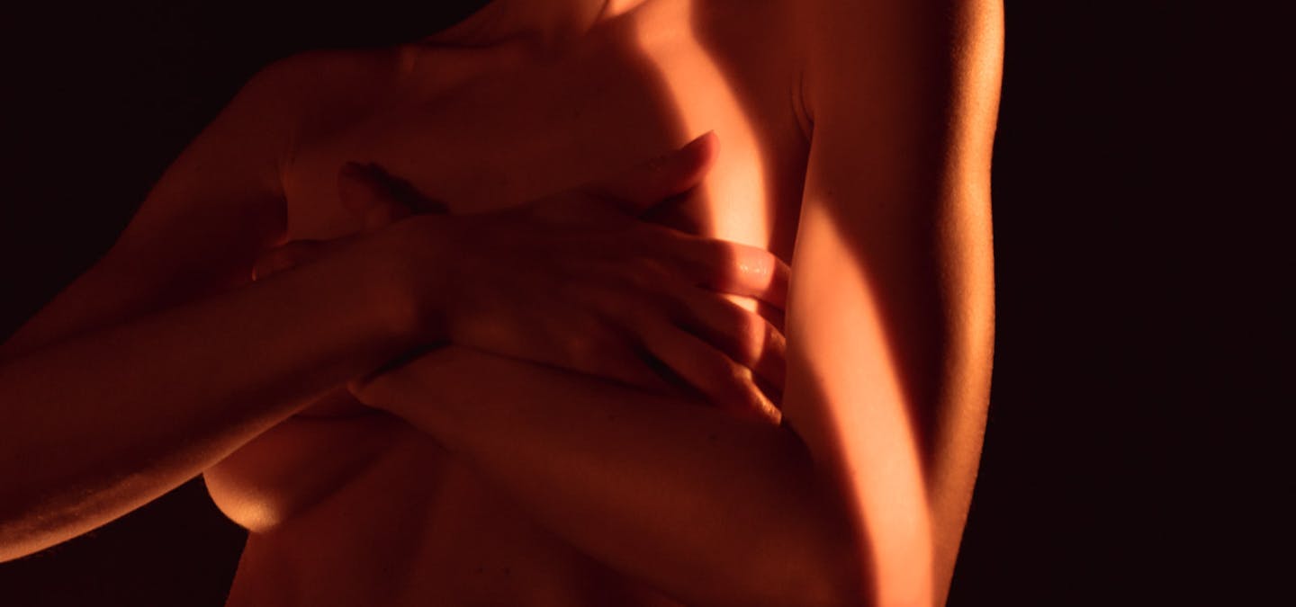 Silhouette d'une jeune femme qui cache ses sains avec ses mains.