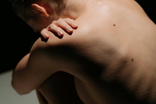 Jeune femme nue recroquevillée sur elle-même.