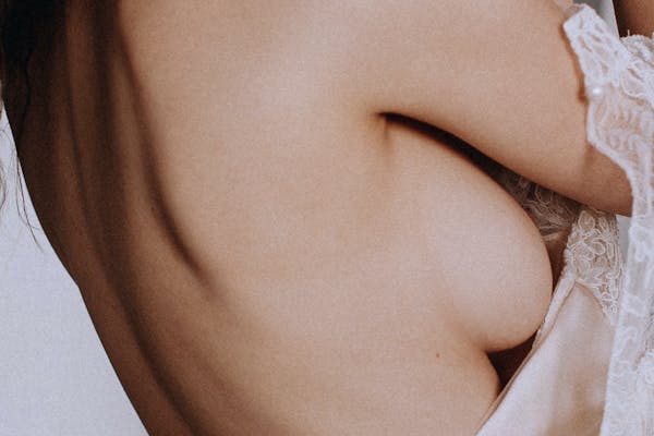 Profil d'une jeune femme presque nue focus sur sa poitrine.