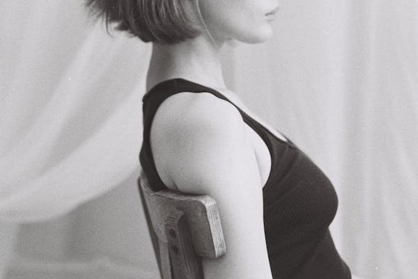 Jeune femme pose assise sur une chaise regardant droit devant elle