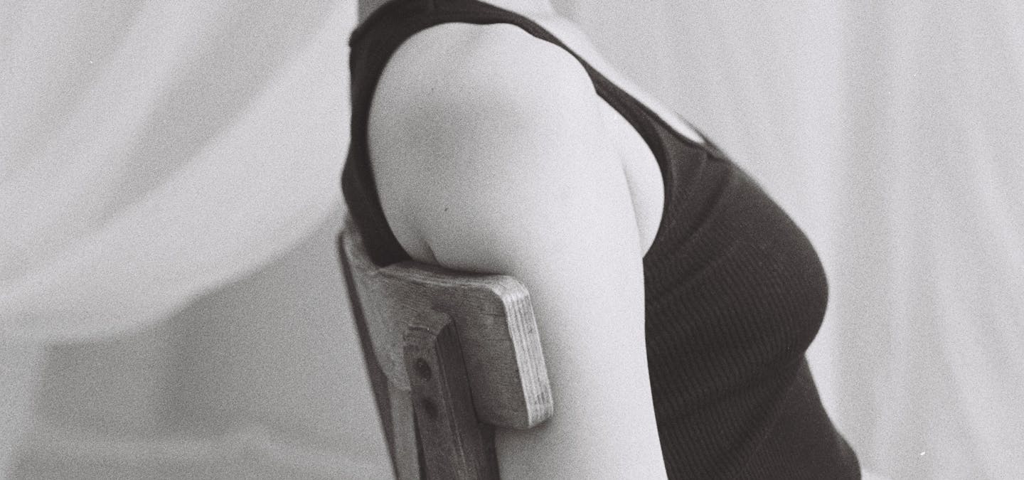 Jeune femme pose assise sur une chaise regardant droit devant elle