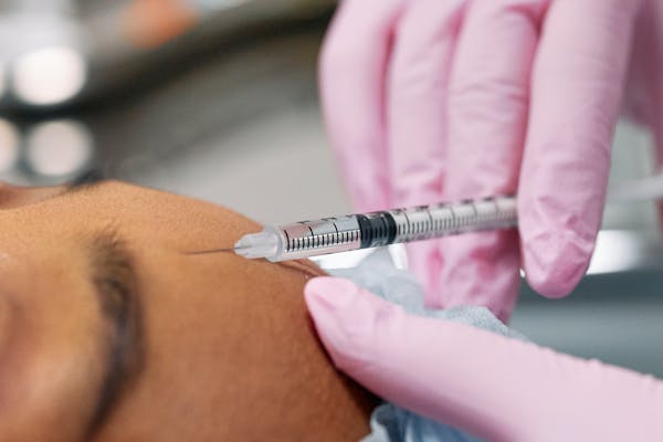 médecin expert réalisant des injections d'acide hyaluronique sur une patiente.