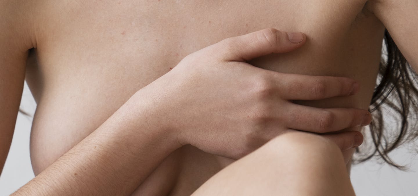 Jeune femme nue avec main sur sa poitrine.