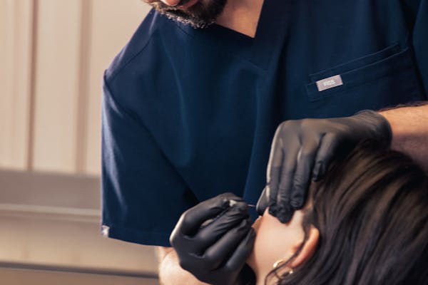Expert réalisant des injections d'acide hyaluronique sur une patiente.