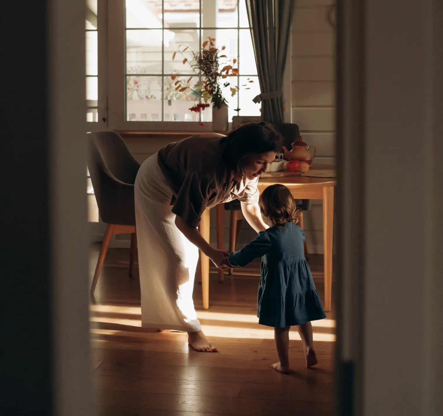 Mãe e filha pequena seguram as mãos em um momento de carinho na sala de estar