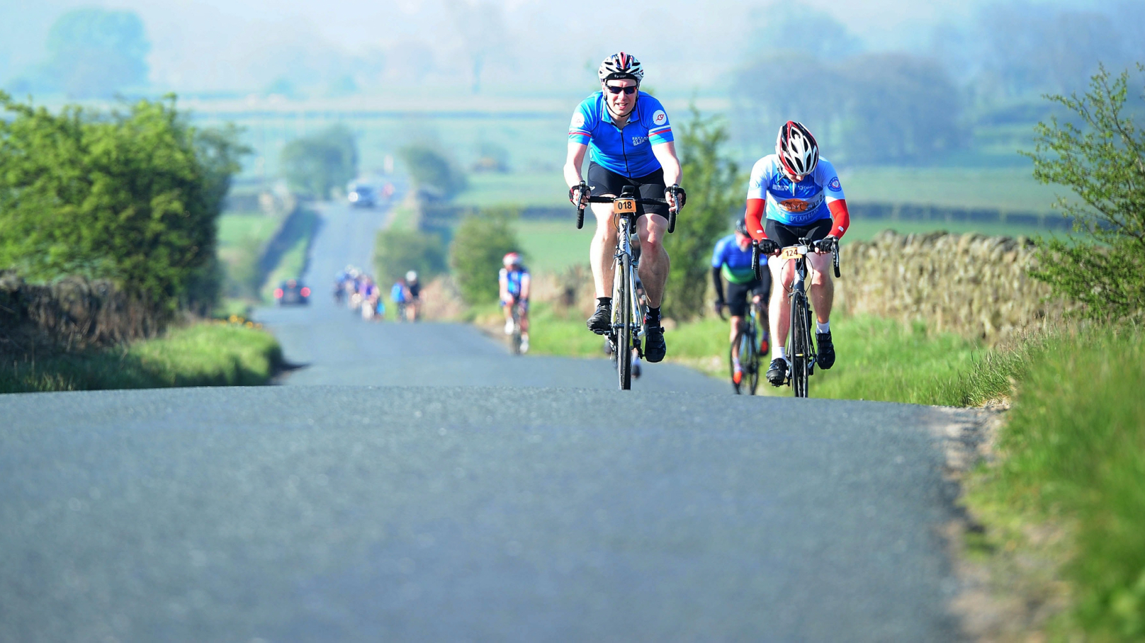 Cyclists cycling up a long country road