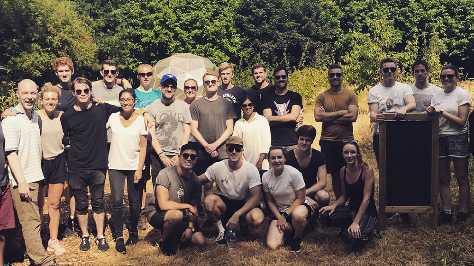 Alfa employees gathered as volunteers standing in a group photo in a garden