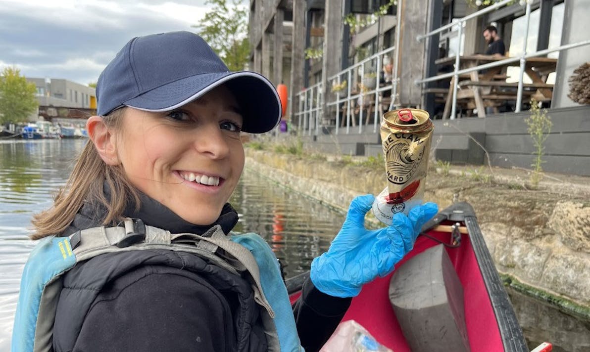 a woman collecting rubbish from a canal
