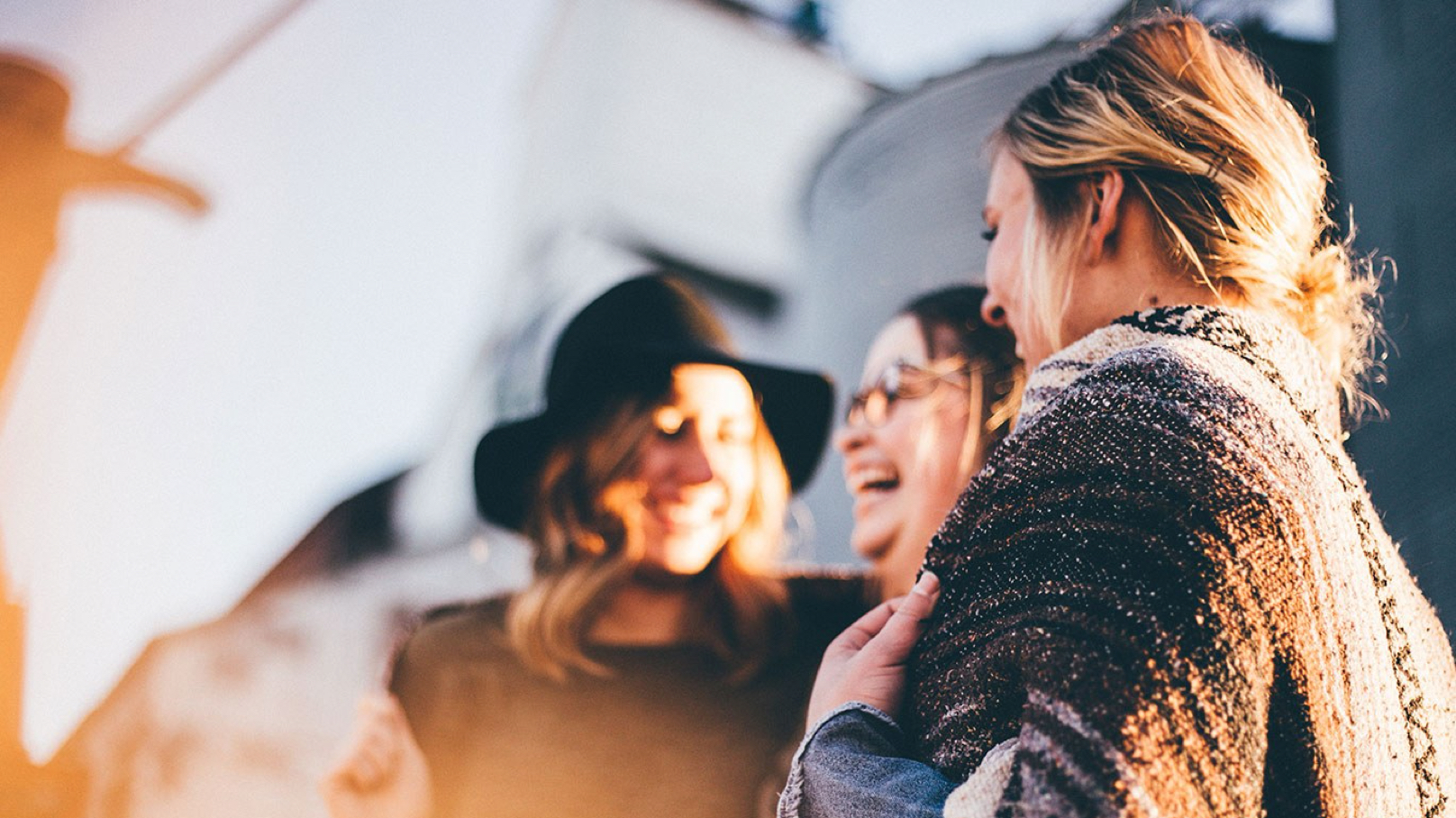 Three women laughing with a sun glow